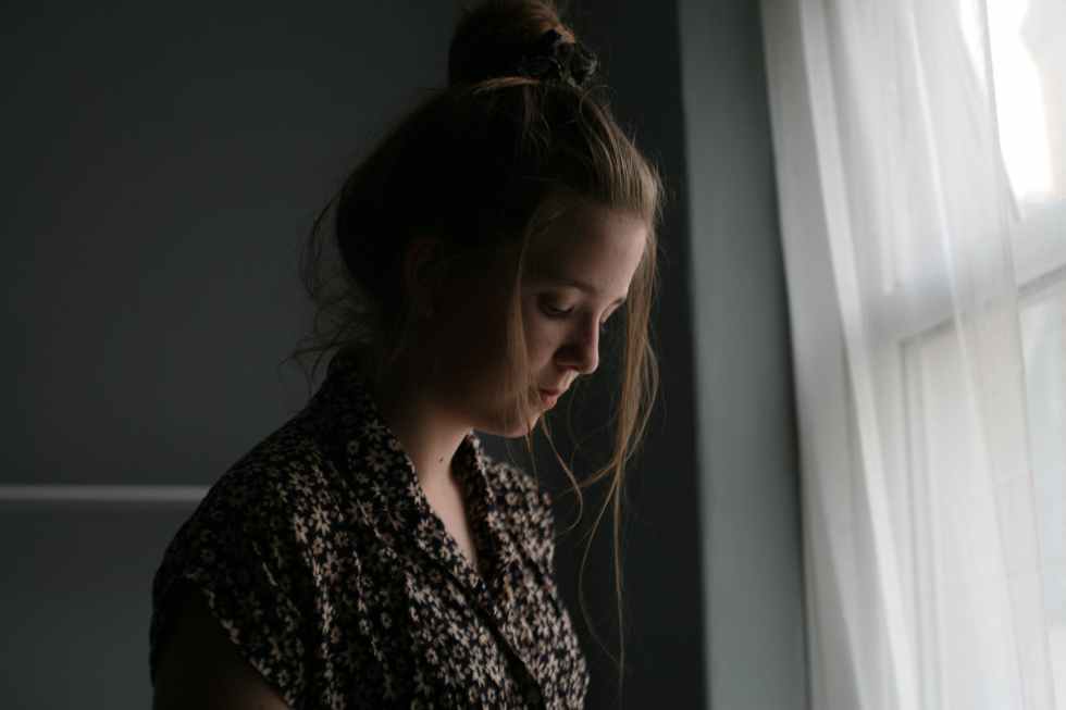 woman standing beside window curtain